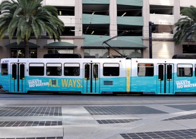 trolley wrapped in campaign graphics passes though a plaza in downtown San Diego